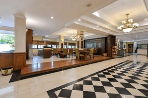 Un vestíbulo de hotel con piso a cuadros, una recepción y zonas de estar.