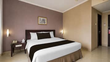 A hotel room with a large bed, bedside tables, a telephone, and a framed picture on the wall.