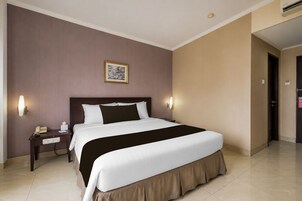 A hotel room with a large bed, bedside tables, a telephone, and a framed picture on the wall.