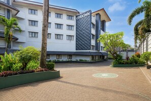 A hotel with a modern design, featuring a prominent sign, a paved courtyard, and surrounding greenery. - Palette Citra Inn (Cikarang)