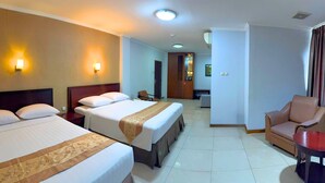 Quarto de hotel com duas camas, uma escrivaninha, uma cadeira e um guarda-roupa.