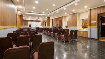 A conference room with rows of chairs, a podium, and a large screen.