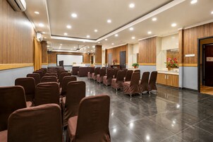Uma sala de conferências com fileiras de cadeiras, um pódio e uma tela grande.