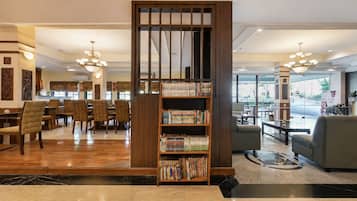 A hotel lobby with a reception desk, seating area, and a bookshelf filled with books.