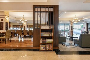 Um saguão de hotel com balcão de recepção, área de estar e uma estante cheia de livros.