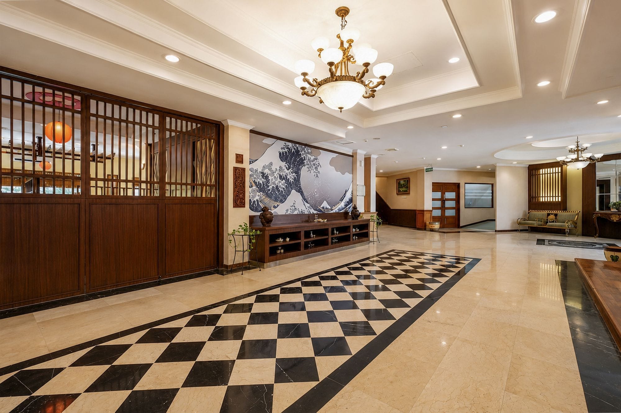 A hotel lobby with a checkered floor, a large wall painting, and a reception desk.