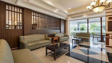A spacious lobby with a leather sofa, a coffee table, and a decorative partition with vertical slats.