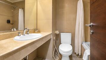 Ein Badezimmer mit Waschbecken, Spiegel, Toilette, Duschvorhang und Handtuchhalter.