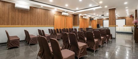 A conference room with rows of chairs, a podium, and a projection screen.