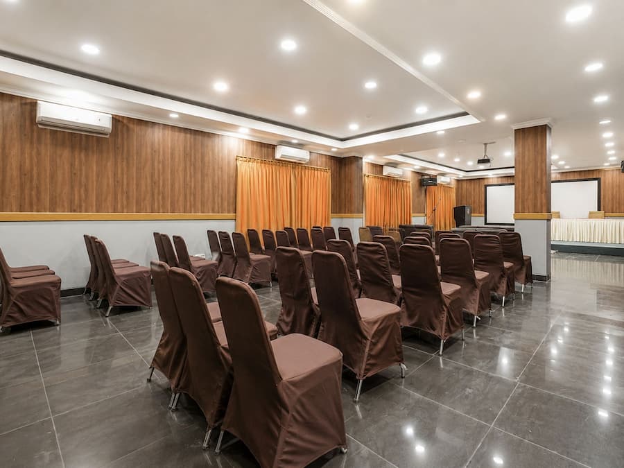 A conference room with rows of chairs, a podium, and a projection screen.