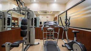 Un gimnasio con diversos equipos de ejercicio, incluyendo una cinta de correr, máquinas de pesas y una bicicleta estática.