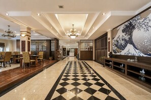 A hotel lobby with a checkered floor, a large wave painting, and a traditional Asian-style gate. - Palette Citra Inn (Cikarang)