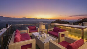 A rooftop terrace with wicker furniture and a tea set, overlooking a mountainous landscape. - View 360 (Kandy)