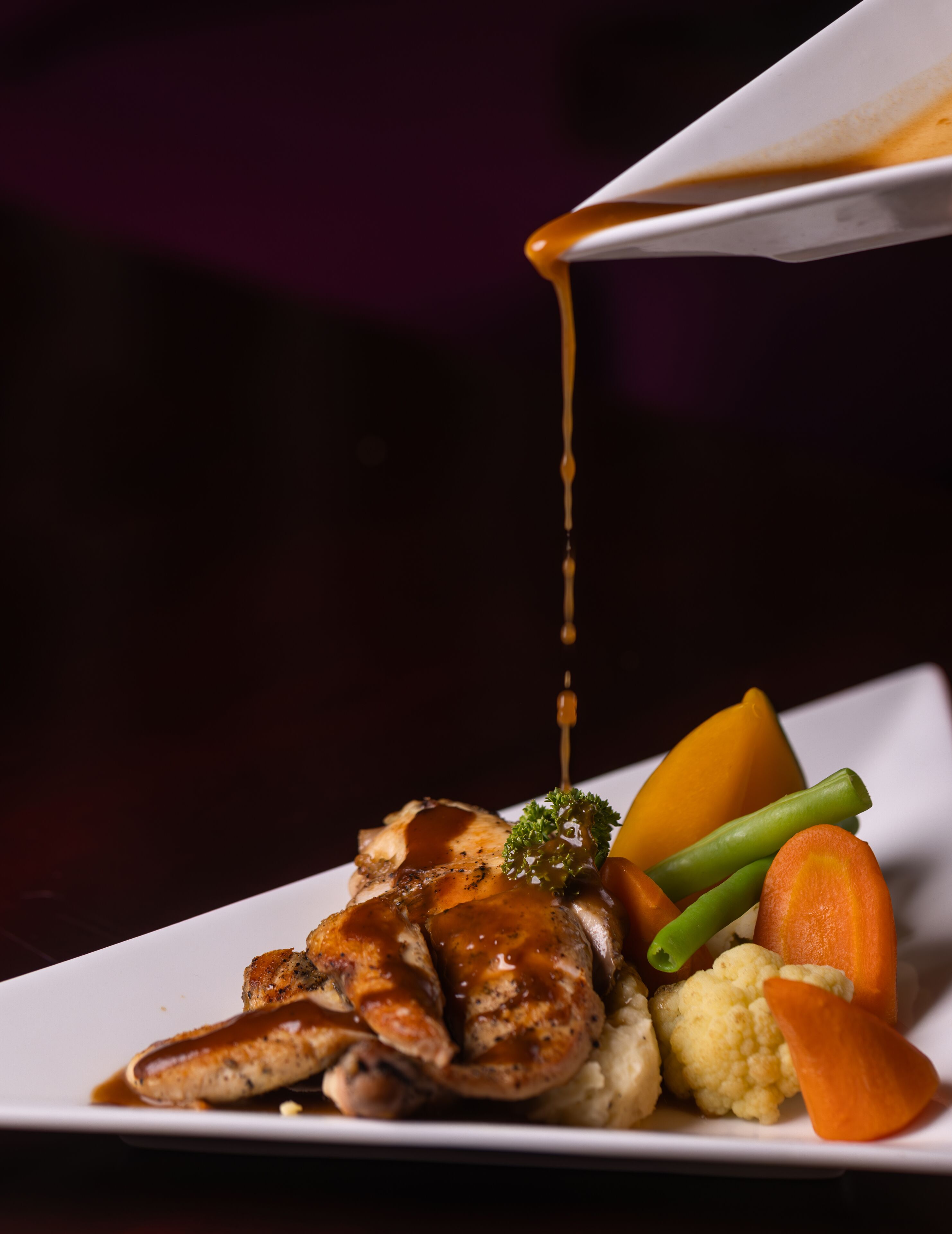 A plate of food with a sauce being poured over it.