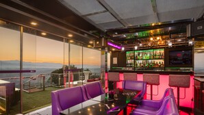 A bar area with purple seating, a bar counter with bottles, and a view of the mountains. - View 360 (Kandy)
