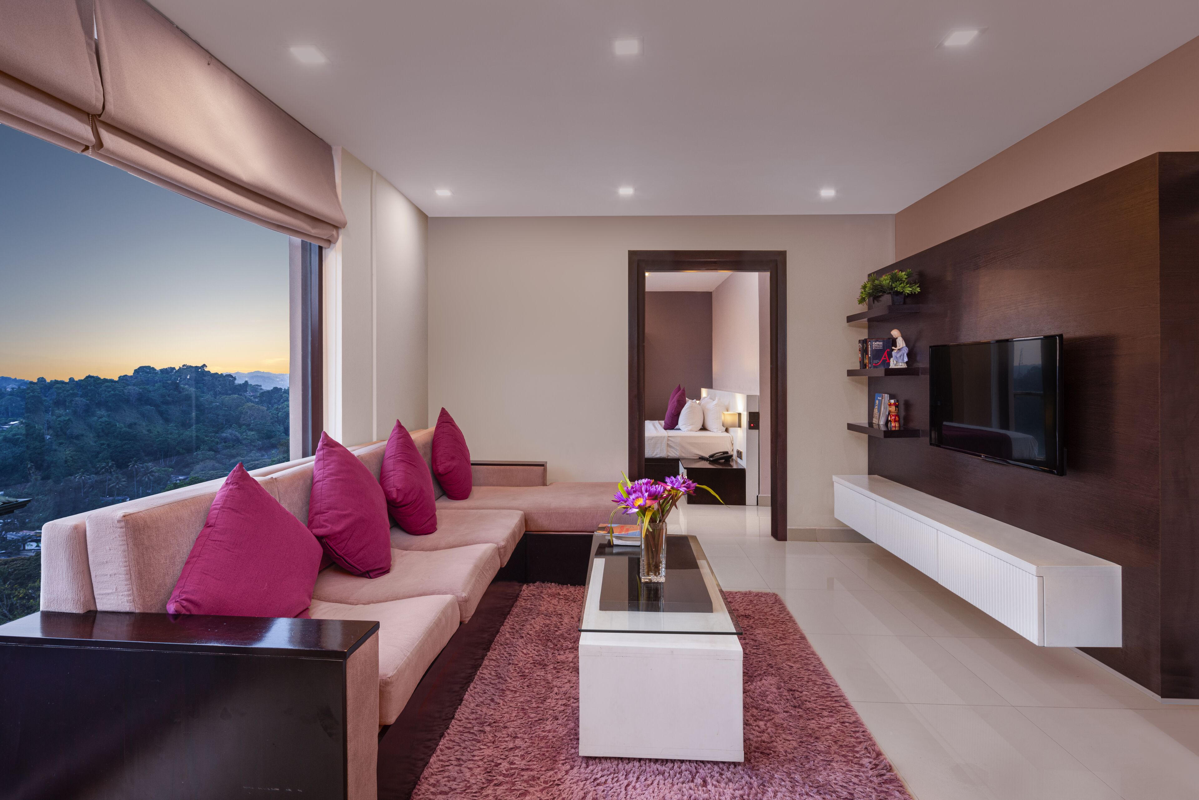 A modern living room with a sofa, a coffee table, a TV, and a view of the cityscape.