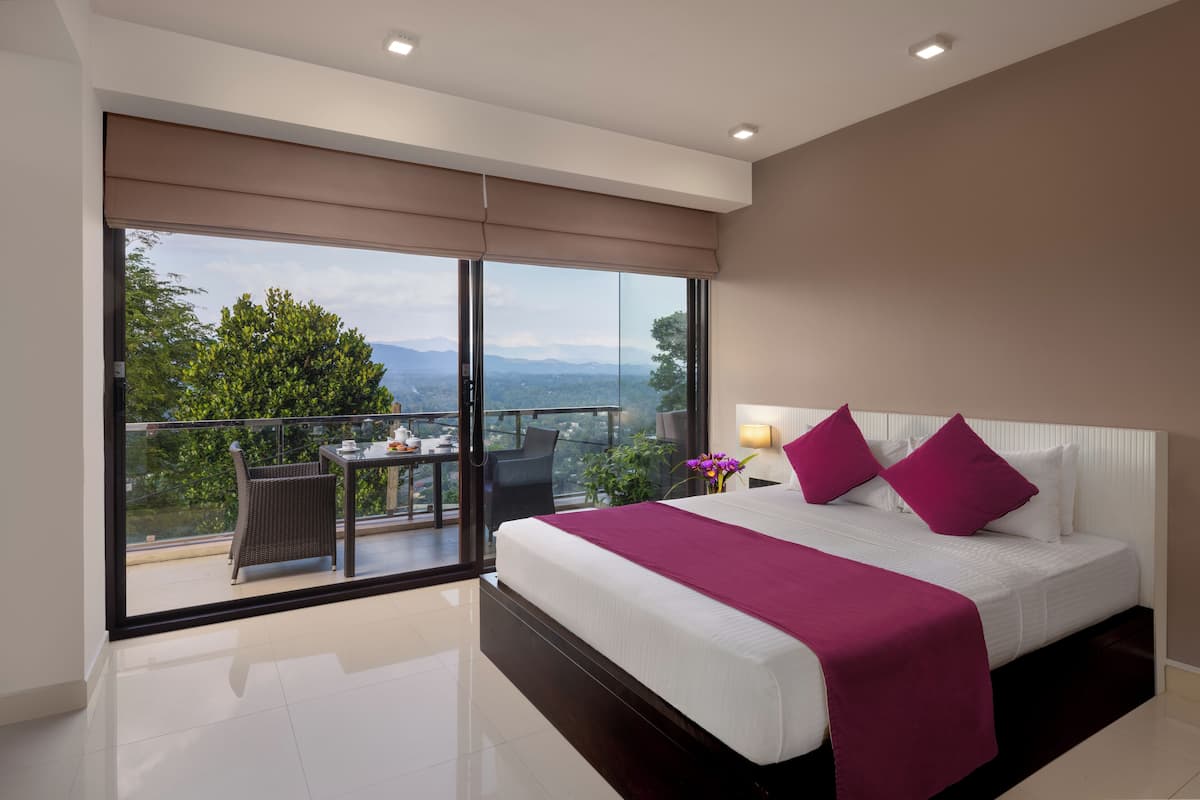 A bedroom with a large bed, a balcony with a table and chairs, and a view of the outdoors.