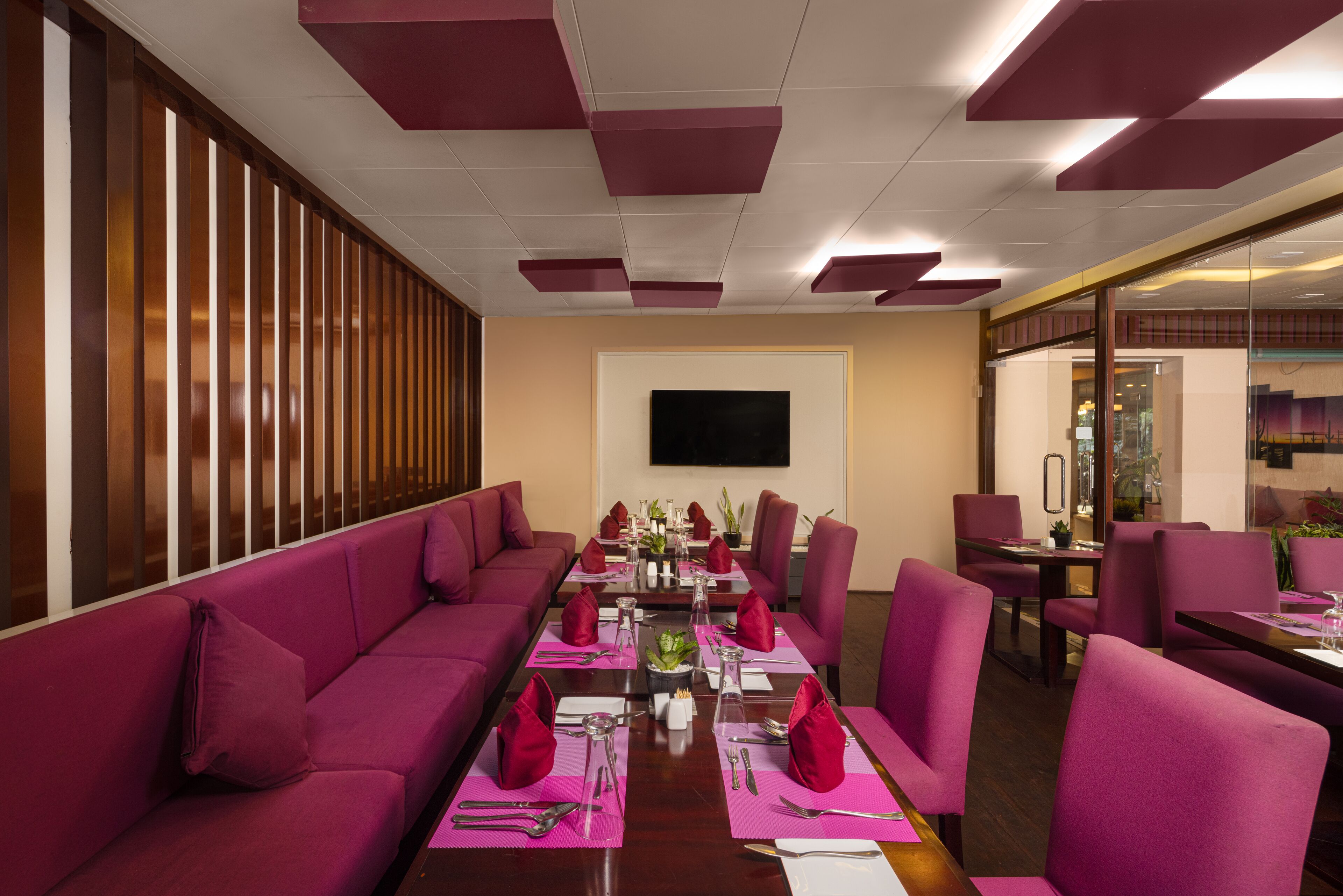 A conference room with a long table set for a meeting, surrounded by purple sofas and chairs.