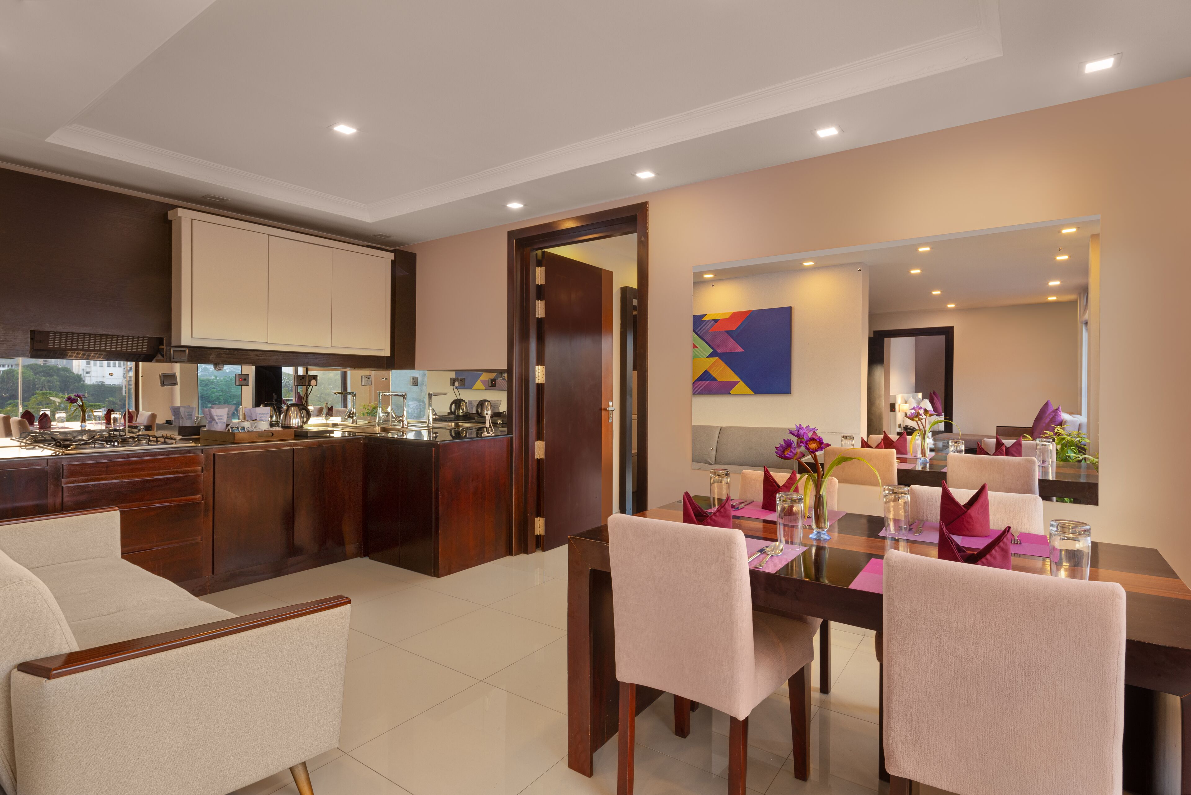 A modern kitchen with dark wood cabinets, a central island, and a dining area with a table set for four.