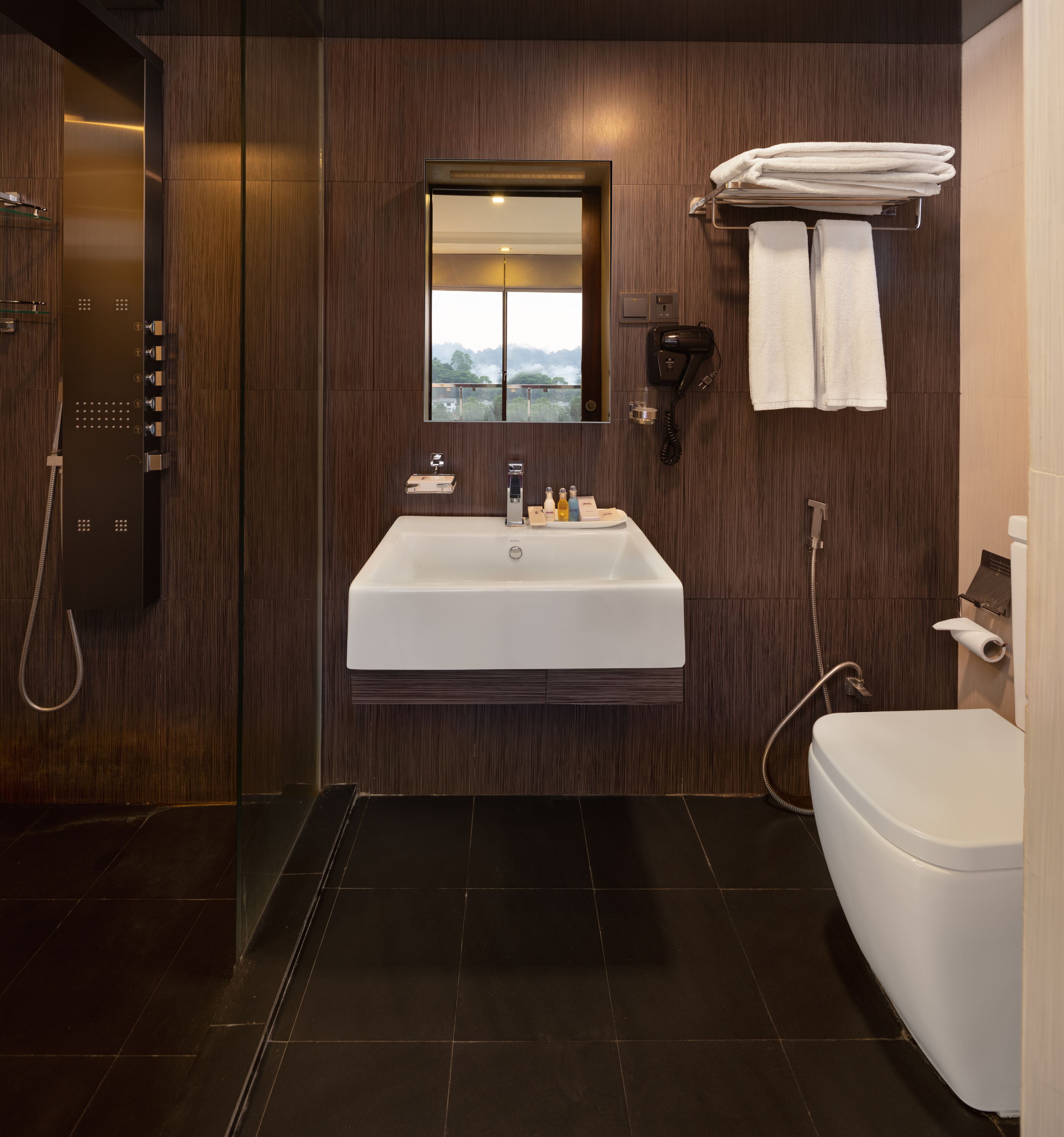 A modern bathroom with a large sink, a mirror, a towel rack, and a shower.