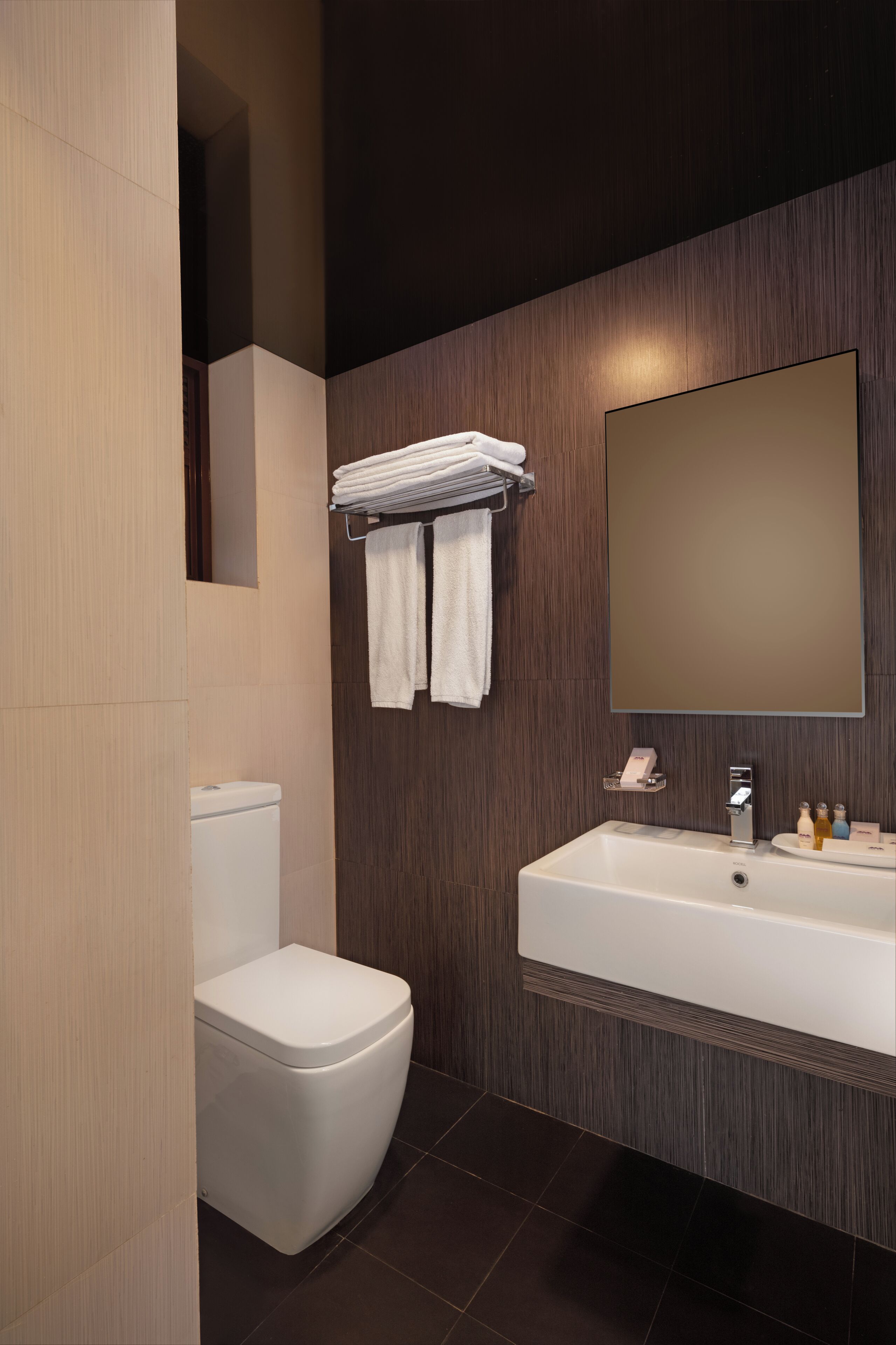 Un baño moderno con inodoro, lavamanos y espejo.