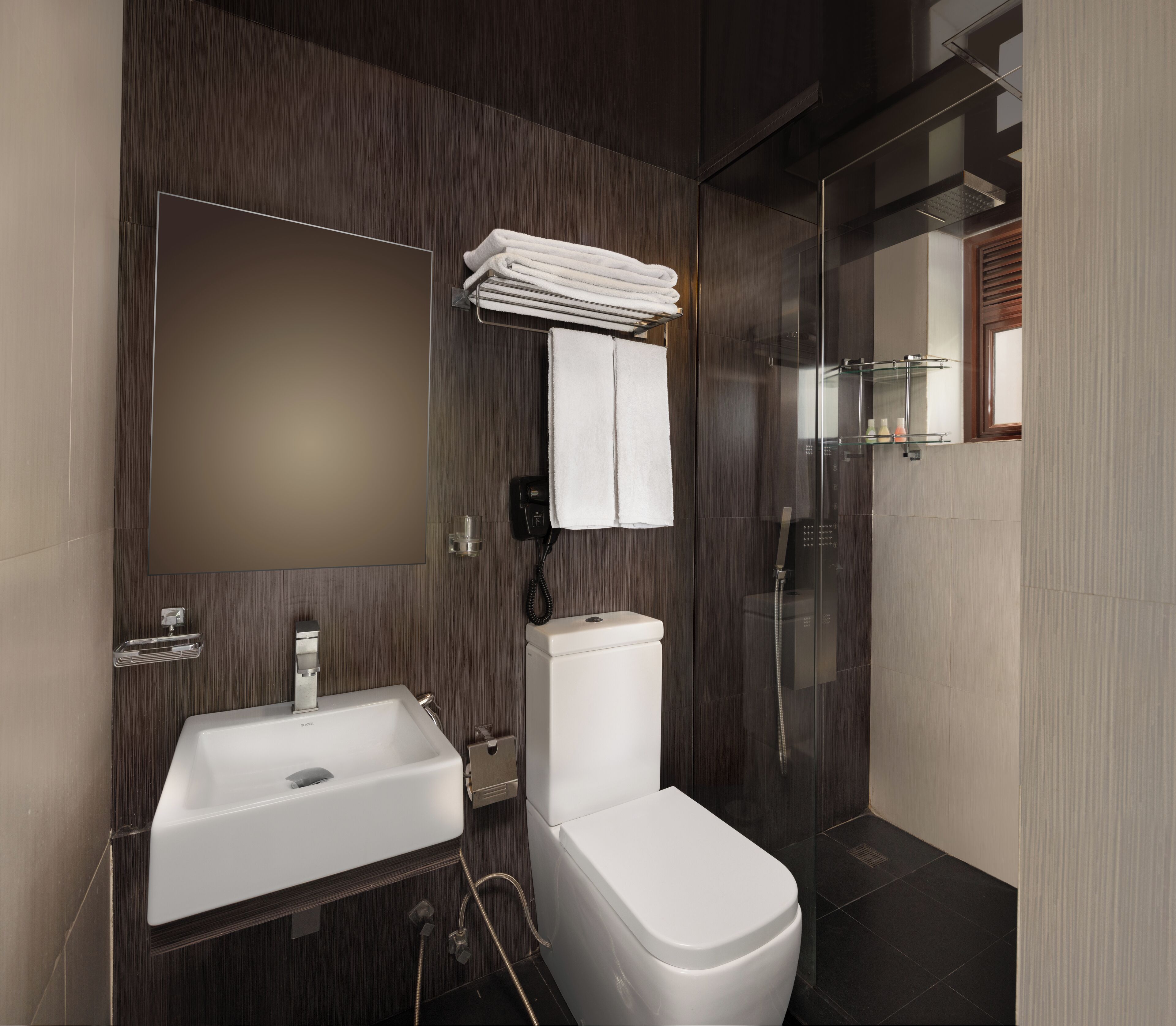 Un baño moderno con lavamanos, inodoro y cabina de ducha de vidrio.