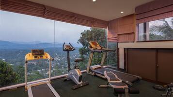 A gym with exercise equipment, large windows, and a view of the mountains.