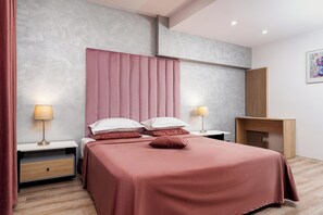 A modern bedroom with a bed, bedside tables, a nightstand, a wooden desk, and a painting on the wall. - Hotel Minerva (Bucharest)
