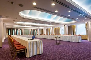 Un salón de conferencias con una larga mesa, sillas y suelo alfombrado.