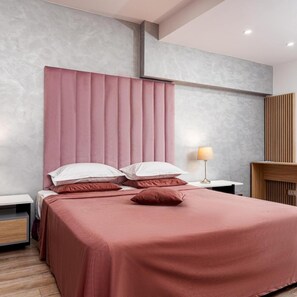 Een moderne slaapkamer met een groot bed, nachtkastje en een lamp.