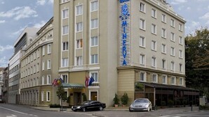 Un hotel con un llamativo letrero que dice 'HOTEL MINERVA', varias ventanas y una zona de acceso cubierta.