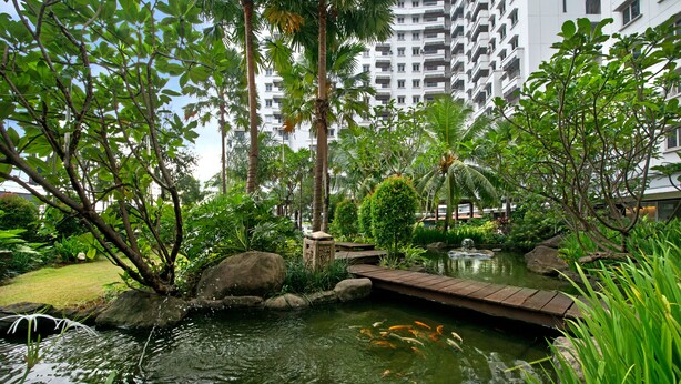 Ein friedlicher Garten mit Teich, Koi-Karpfen und einer Holzbrücke.