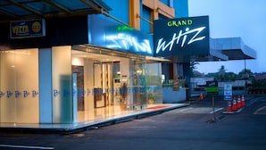 Ein Hotel Eingang mit einem großen, beleuchteten Schild, auf dem "GRAND" und "Grand Ritz" steht.