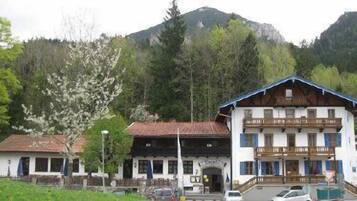 A traditional building with a sloped roof, a balcony, and a mountain backdrop.