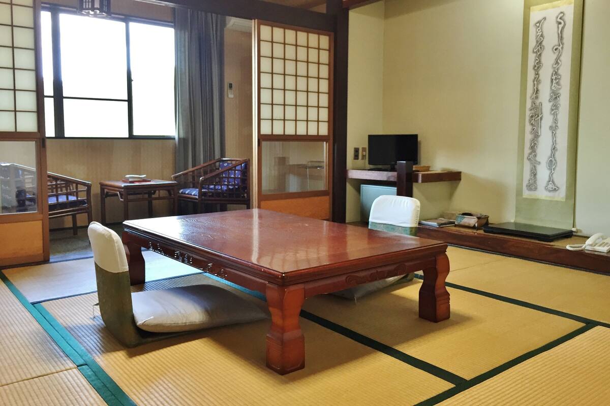 A traditional Japanese room with tatami flooring, a low wooden table, and a sliding door.