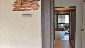 A wooden plaque with "703 YOSHINO" on a textured wall, a traditional sliding door, and a tatami mat floor.