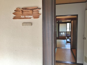 A wooden plaque with "703 YOSHINO" on a textured wall, a traditional sliding door, and a tatami mat floor. - Ebisukan (Yoshino)