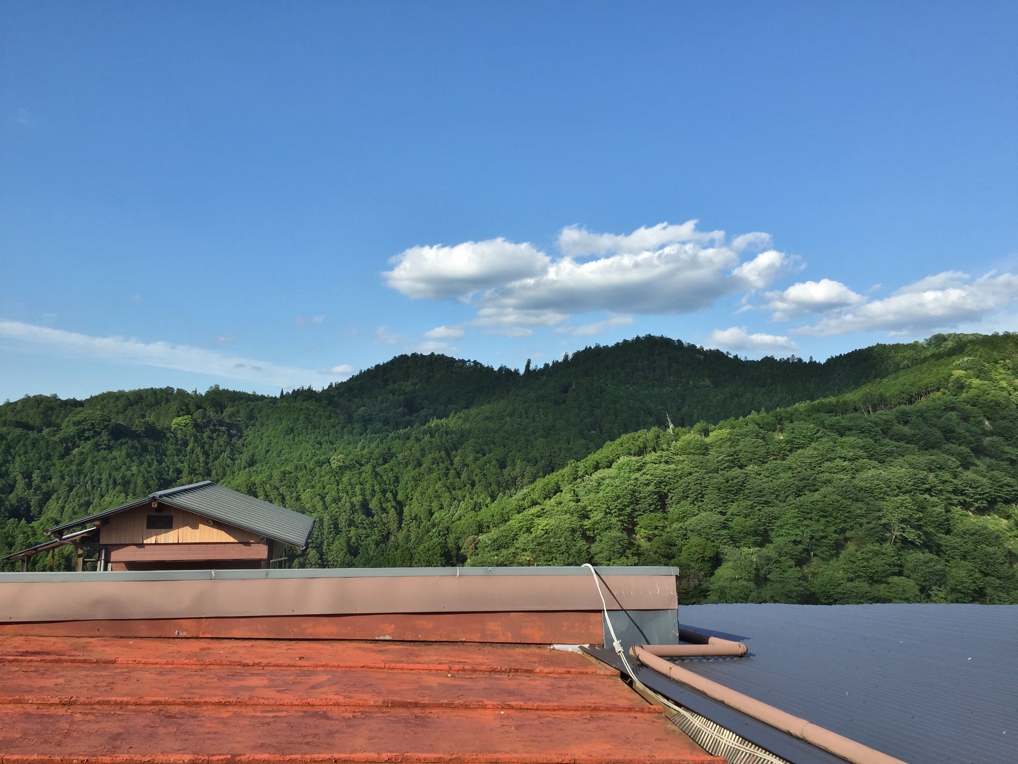 A building with a sloped roof and a view of a forested hill.