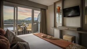 Une chambre d’hôtel comprenant un lit, un bureau, une télévision, un balcon avec une table et des chaises, et offrant une vue sur les montagnes.