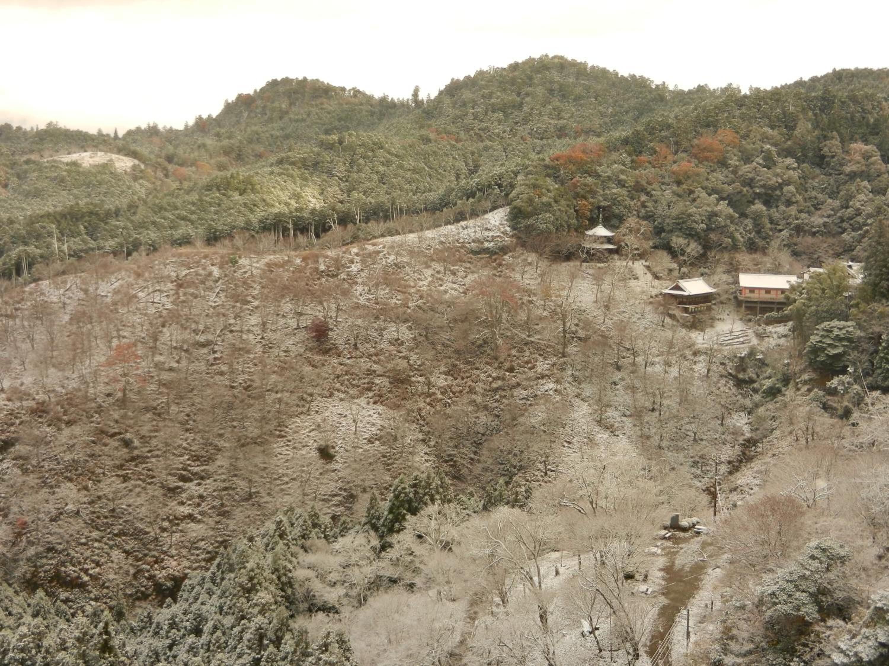 A mountainous landscape with sparse vegetation and a few buildings with traditional architecture.