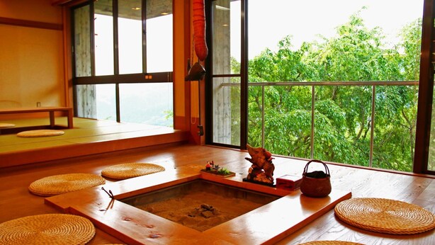 A traditional Japanese room with tatami flooring, a shoji screen, and a view of lush greenery. - Hounkan (Yoshino)