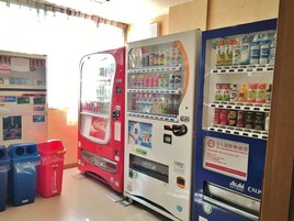 A vending machine area with various drink options, including Coca-Cola and Asahi soft drinks.