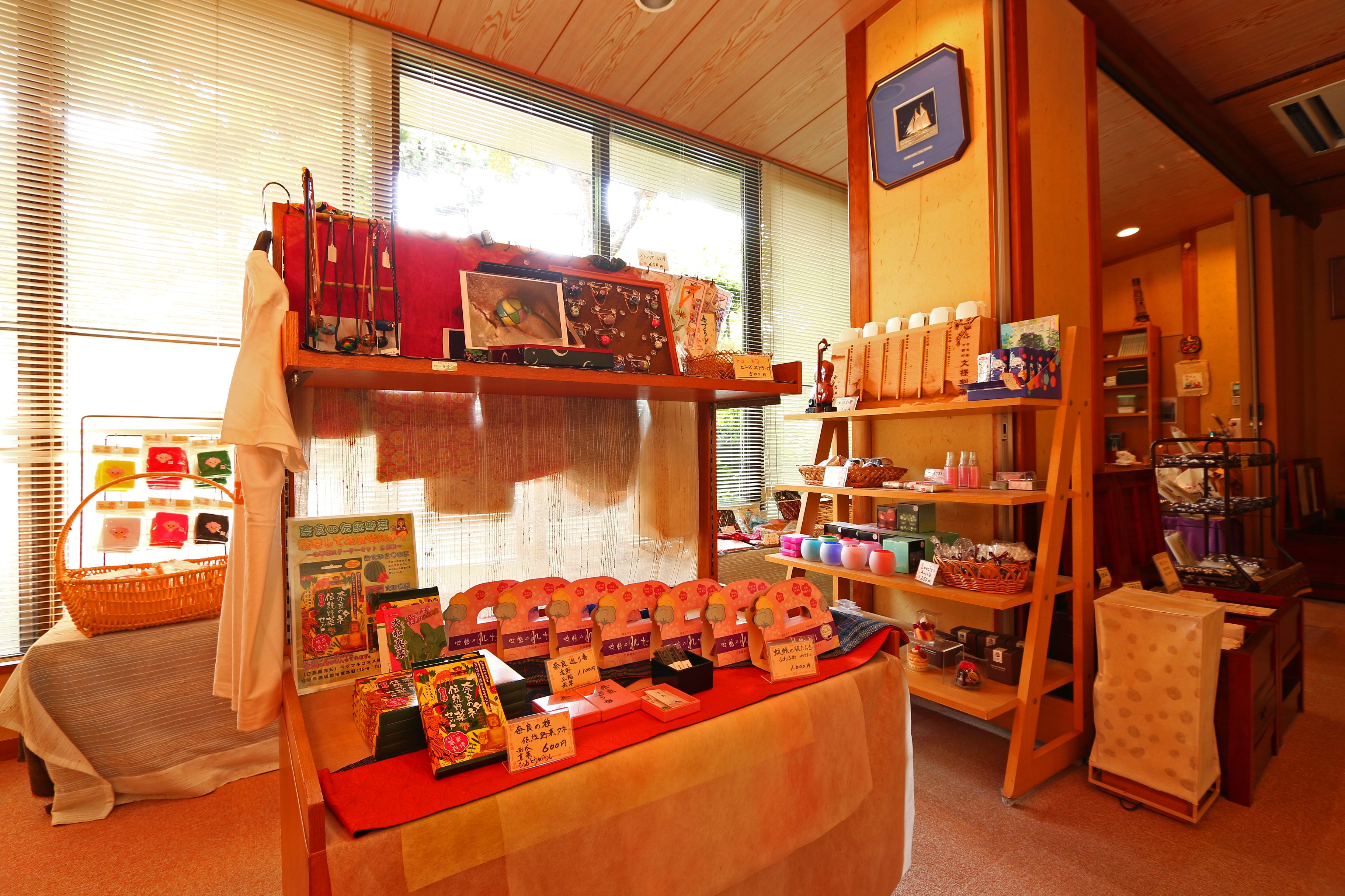 Una habitación con una cama, una mesa con objetos varios, y estantes con botellas y cajas.