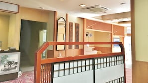 A hotel lobby with a reception desk, a staircase, and a wall with decorative elements. - Hounkan (Yoshino)