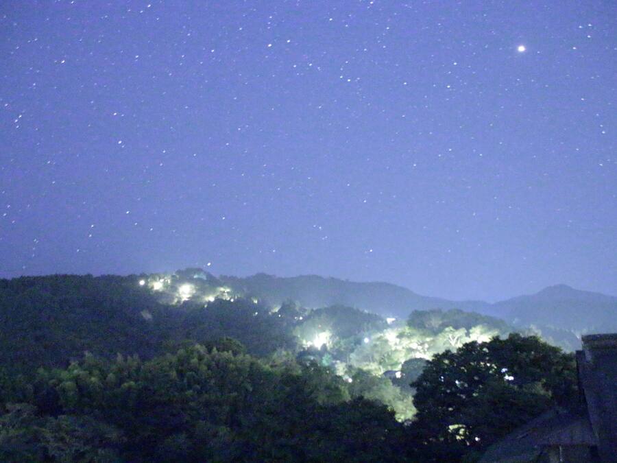 Cielo nocturno con estrellas y un paisaje urbano al fondo.