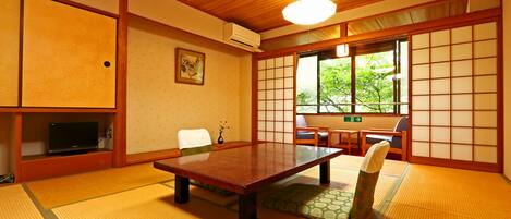 A tatami mat room with a low table, chairs, and a sliding door.
