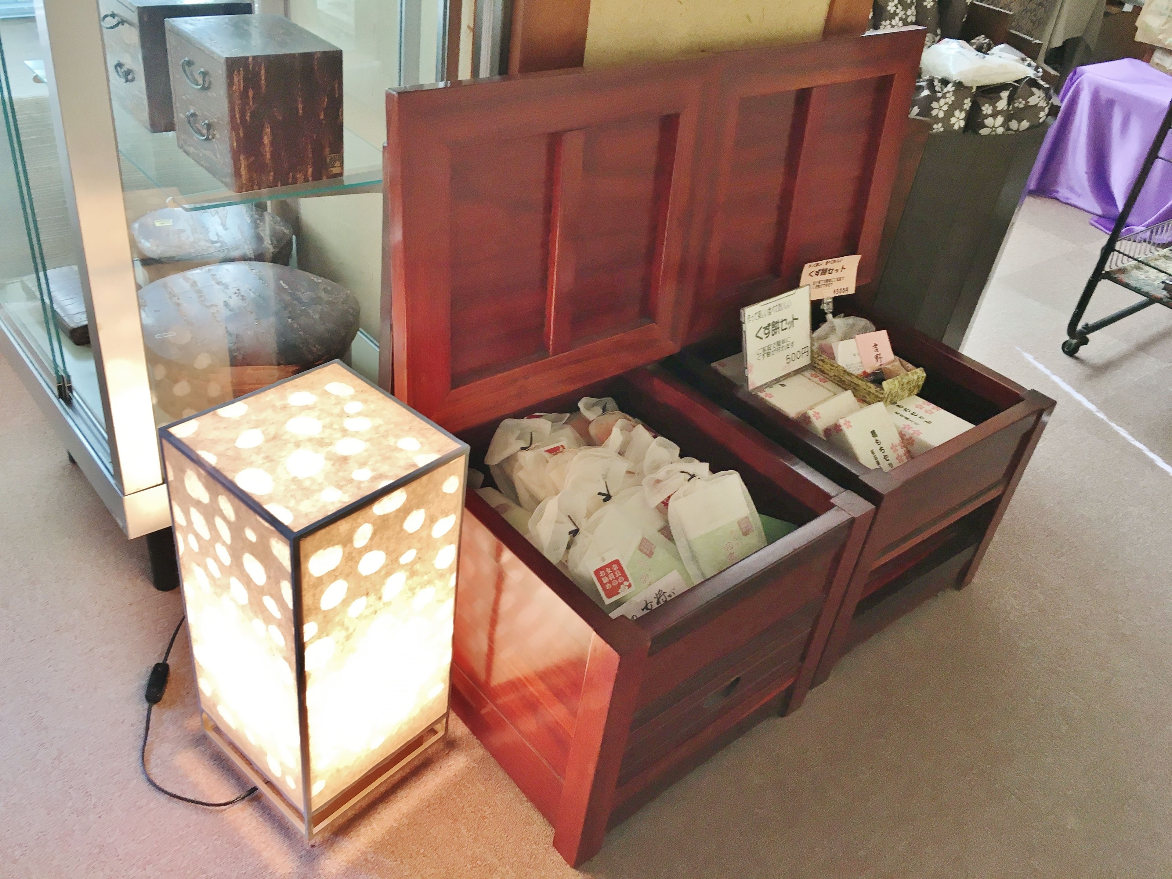 A display of various items, including a wooden cabinet with labeled boxes and a glass display case with a polka dot lamp.