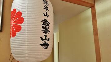 A white paper lantern with black Japanese characters and a red flower design.