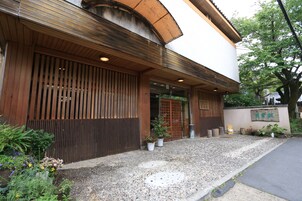 A traditional Japanese building with a wooden facade, a gravel entrance, and potted plants.