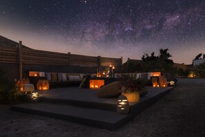 Un espacio al aire libre con mesas y sillas, ofreciendo vistas del cielo nocturno iluminado por velas y faroles.